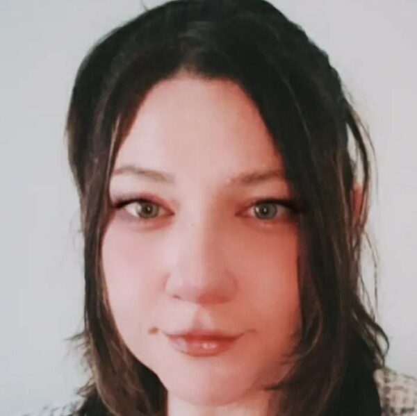 Person with long hair smiling at camera.