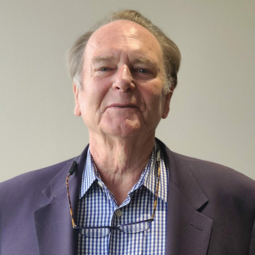 Man in checkered shirt and blazer smiling