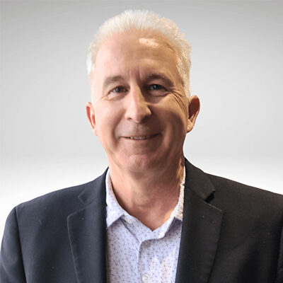 Smiling man in suit against gray background.