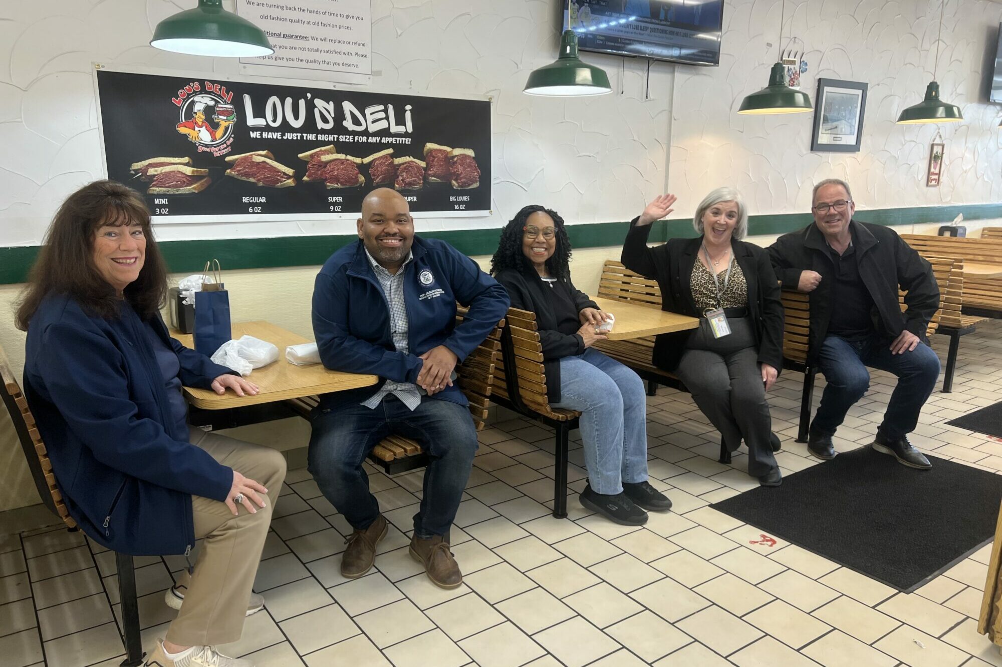 Group of people smiling in a deli.